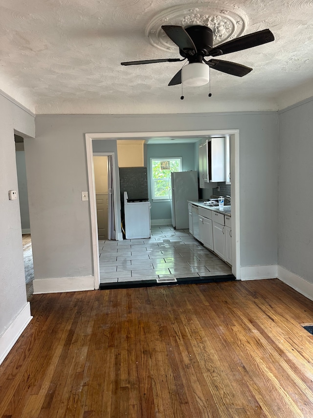 unfurnished room featuring a textured ceiling, ceiling fan, wood finished floors, and baseboards