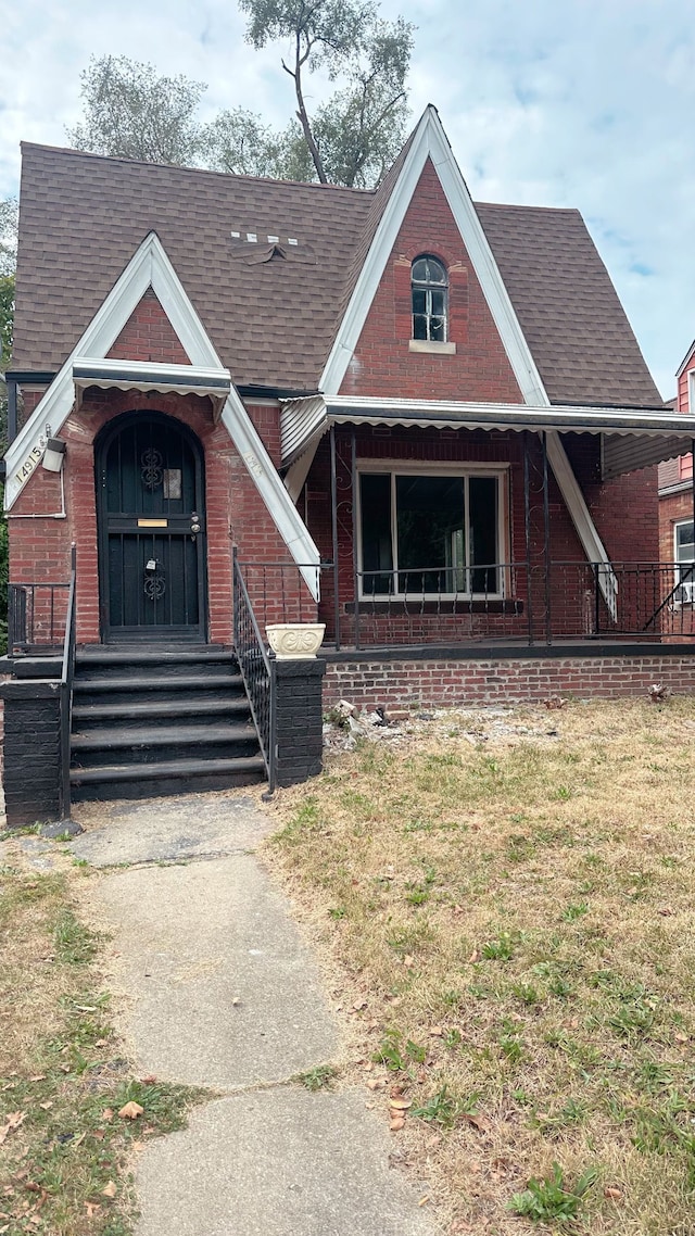 view of front facade featuring roof with shingles and brick siding