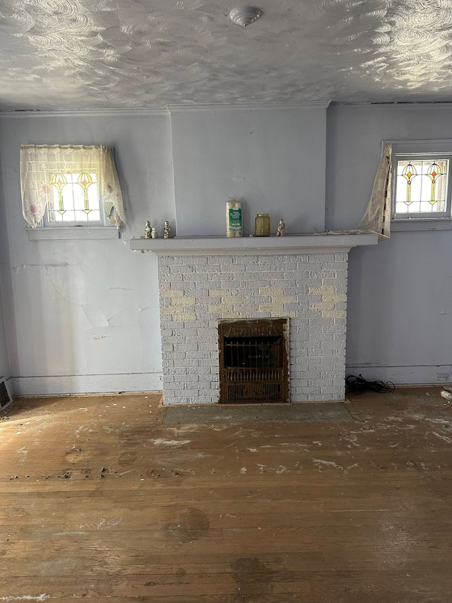 unfurnished living room featuring a textured ceiling, a fireplace, and wood finished floors