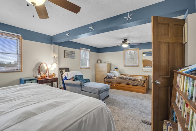 carpeted bedroom featuring visible vents, ceiling fan, and a textured ceiling