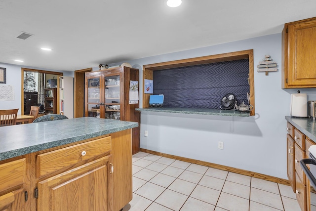 kitchen with dark countertops, light tile patterned floors, visible vents, and range