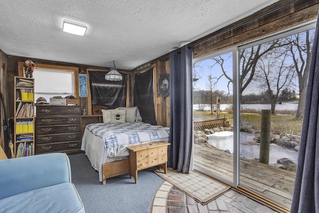 bedroom with access to exterior, wooden walls, and a textured ceiling