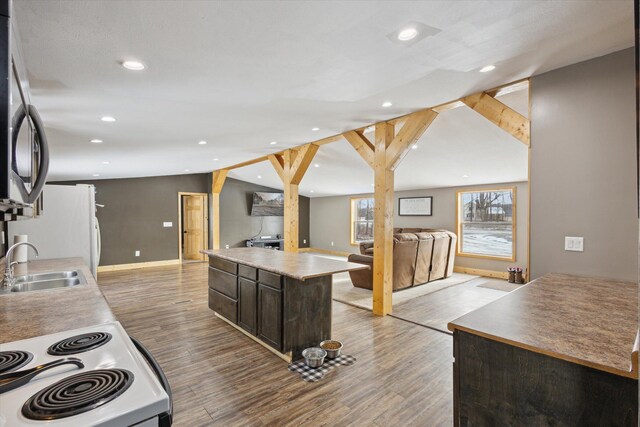 4087 Amble Rd, Coral, MI 49322 - kitchen with white appliances, a sink, open floor plan, dark brown cabinets, and a center island