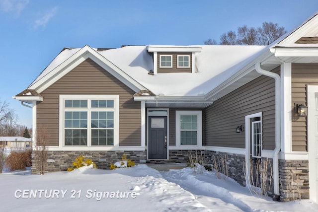 snow covered property entrance featuring stone siding