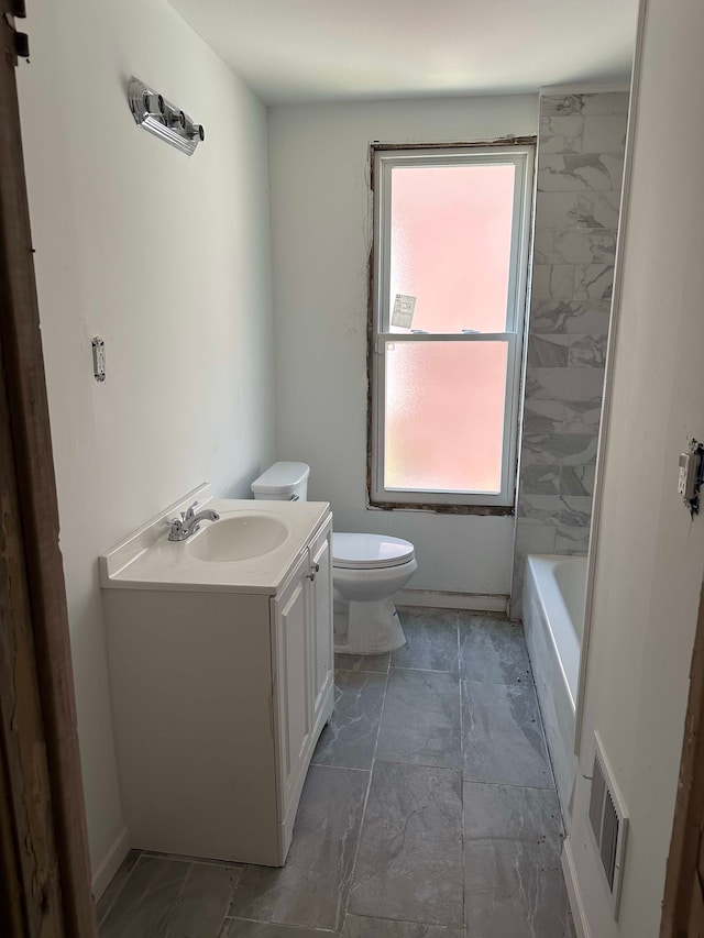 bathroom featuring toilet, a washtub, vanity, and visible vents