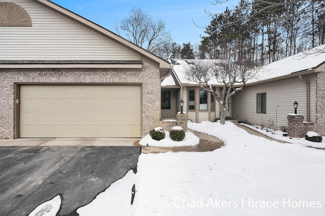 single story home featuring aphalt driveway, brick siding, and an attached garage