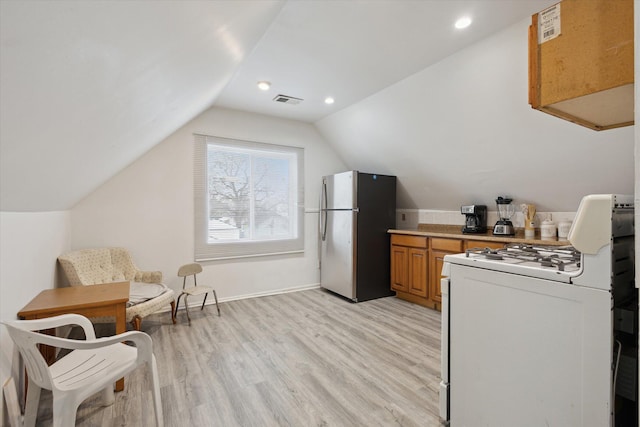 kitchen with light wood-style flooring, white gas range, freestanding refrigerator, and brown cabinets