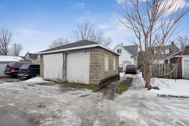 snow covered garage featuring fence