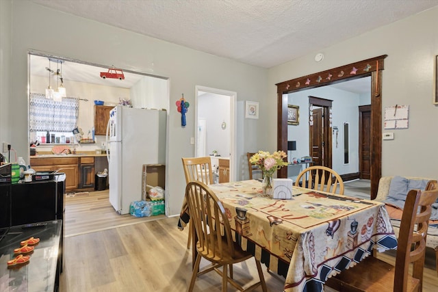 dining area featuring light wood-type flooring and a textured ceiling