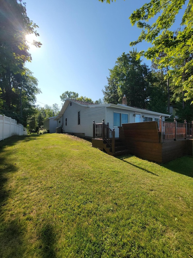 back of house featuring a lawn, a chimney, and fence