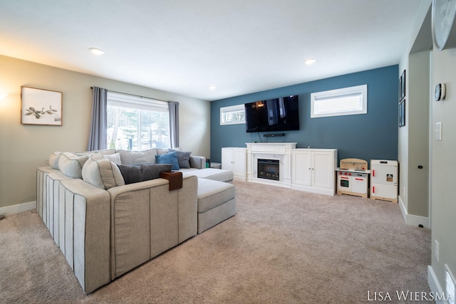 living area featuring a glass covered fireplace, light carpet, baseboards, and recessed lighting