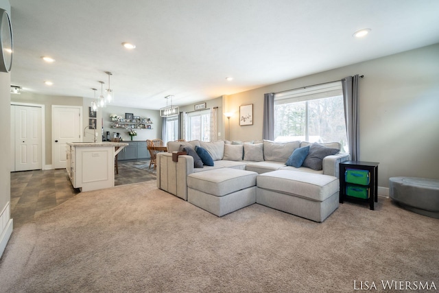 carpeted living area with baseboards, a sink, and recessed lighting