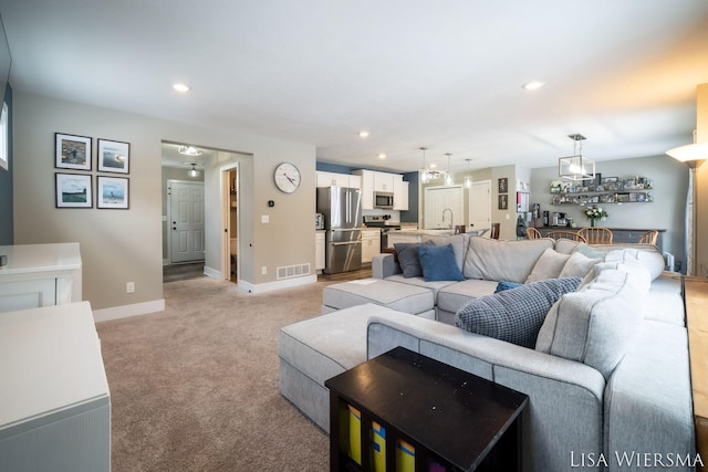 living room with light carpet, recessed lighting, visible vents, and baseboards