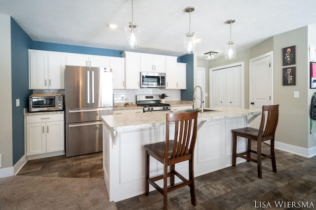 kitchen featuring appliances with stainless steel finishes, light countertops, white cabinets, and decorative light fixtures