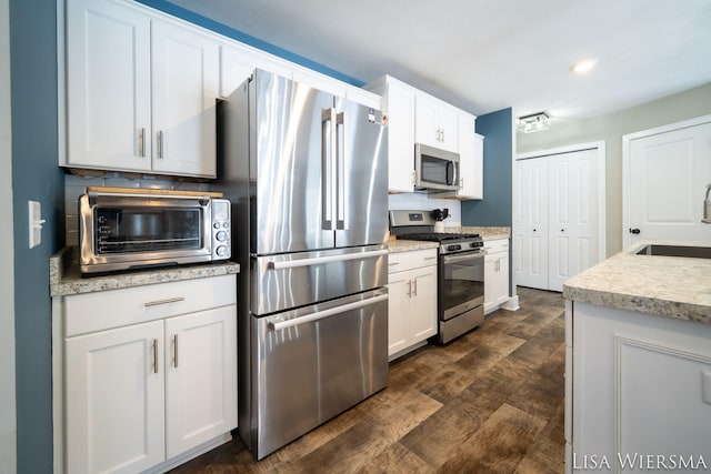 kitchen featuring a toaster, stainless steel appliances, a sink, white cabinetry, and light countertops