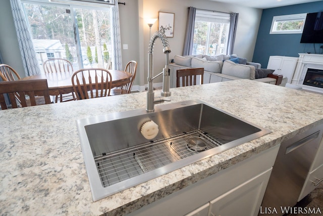 kitchen with dishwasher, a fireplace, open floor plan, and a sink