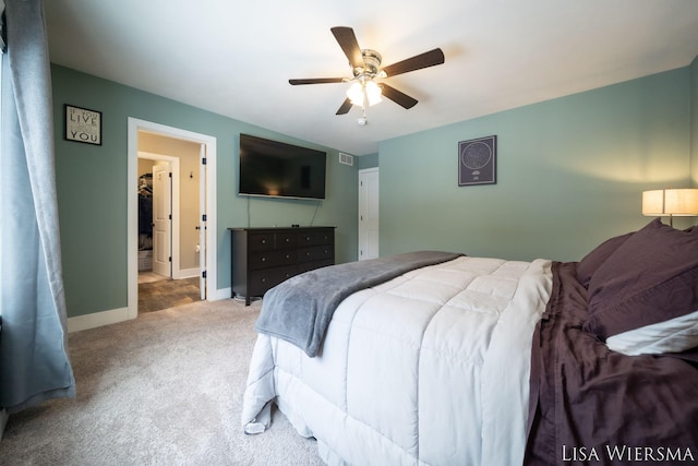 bedroom with light carpet, ceiling fan, ensuite bath, and baseboards