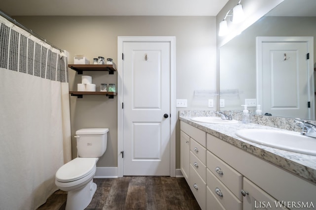 full bathroom featuring double vanity, a sink, toilet, and wood finished floors