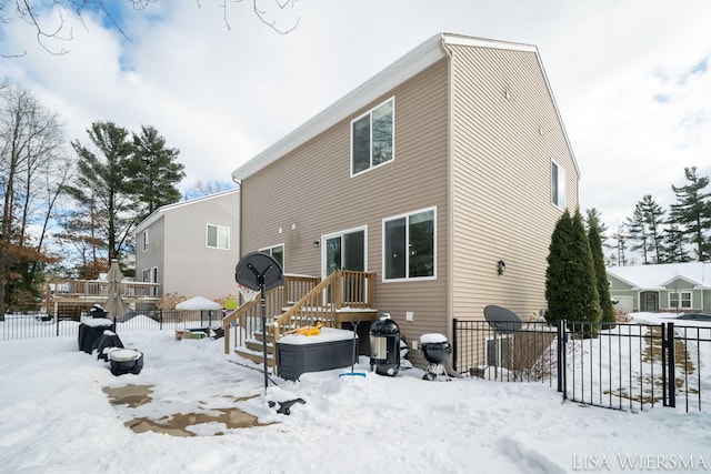 snow covered house featuring fence