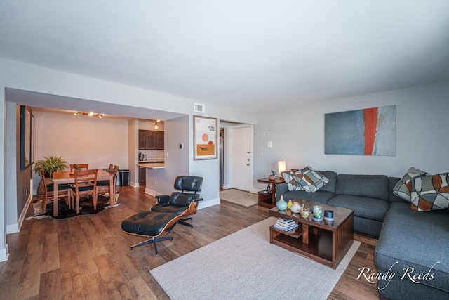 living room featuring visible vents, baseboards, and wood finished floors