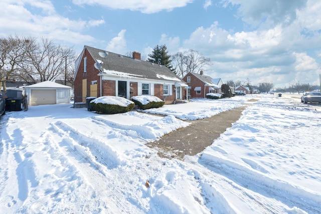 view of front of house featuring an outbuilding, brick siding, a chimney, and a detached garage