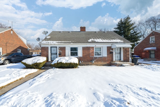 bungalow-style house with brick siding, a chimney, and roof with shingles