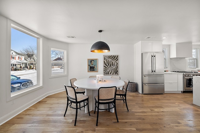 dining area featuring baseboards, visible vents, and light wood-style floors