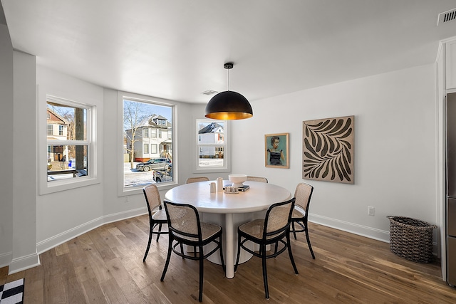 dining room featuring dark wood-type flooring, visible vents, and baseboards