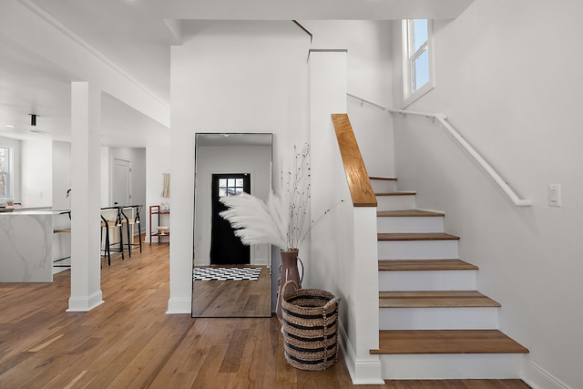 stairway with a towering ceiling, hardwood / wood-style floors, baseboards, and a wealth of natural light