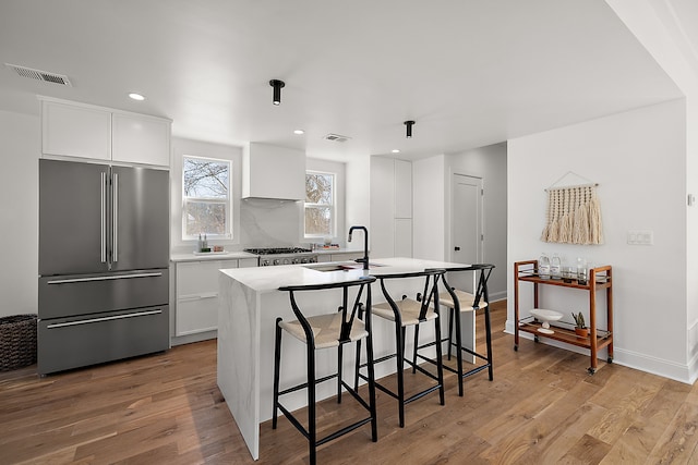 kitchen with light wood-style flooring, high end refrigerator, visible vents, and a sink