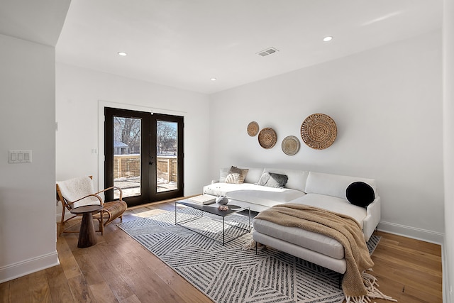 living area with french doors, visible vents, wood-type flooring, and baseboards