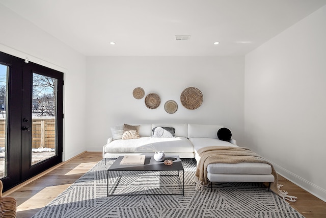 living room featuring light wood-style floors, baseboards, visible vents, and french doors