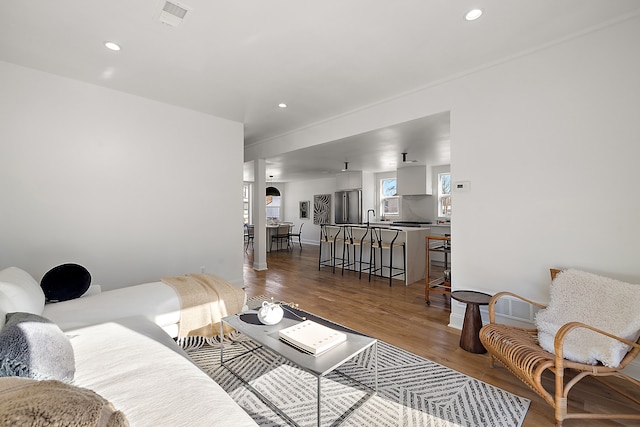 living room featuring visible vents, arched walkways, wood finished floors, and recessed lighting