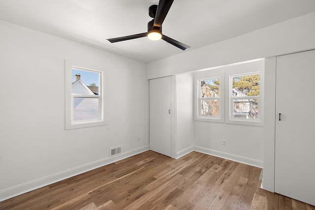 unfurnished bedroom with light wood-style floors, visible vents, baseboards, and a ceiling fan