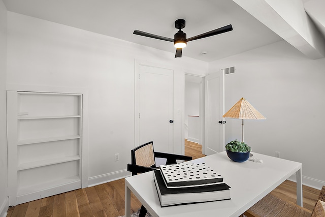 home office featuring baseboards, wood finished floors, visible vents, and a ceiling fan