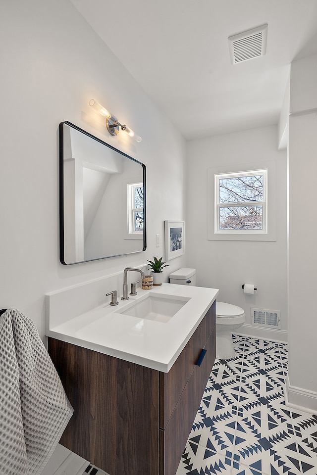 bathroom with baseboards, visible vents, vanity, and toilet