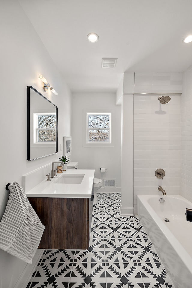 full bath featuring toilet, double vanity, a sink, and visible vents