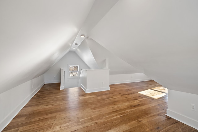 additional living space featuring lofted ceiling, baseboards, and hardwood / wood-style floors