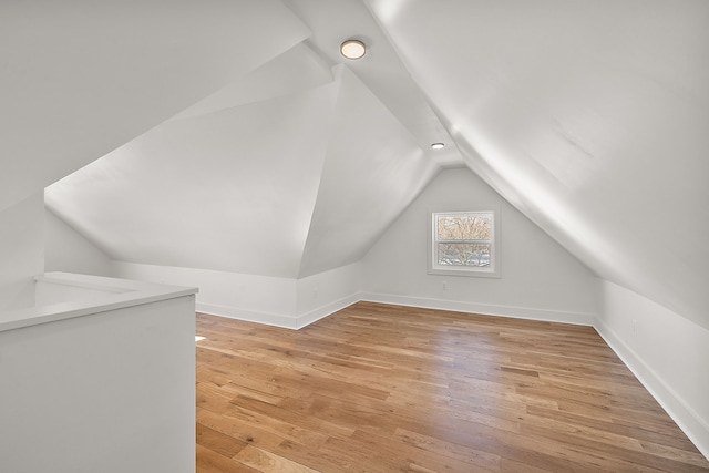 bonus room featuring vaulted ceiling, baseboards, and light wood-style floors