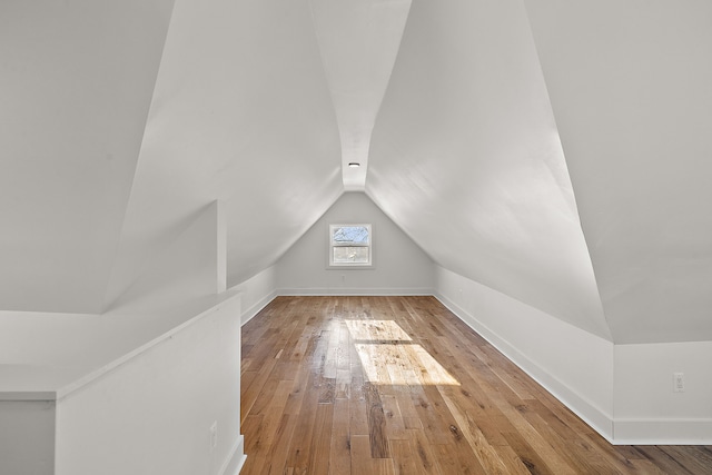 additional living space featuring baseboards, vaulted ceiling, and hardwood / wood-style floors