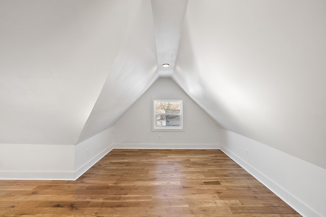 bonus room featuring lofted ceiling, light wood-style floors, and baseboards