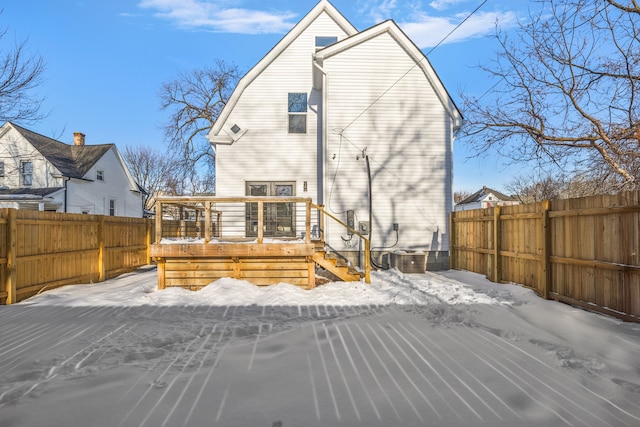 snow covered rear of property featuring a fenced backyard and a wooden deck