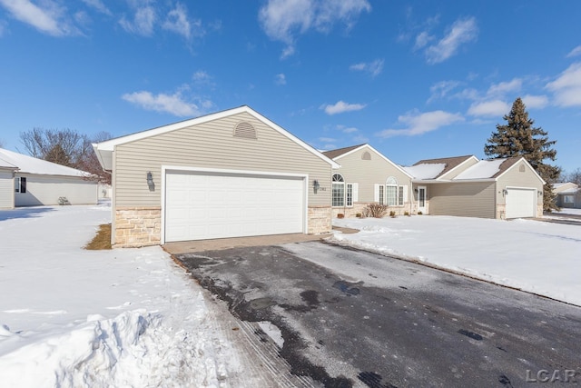 ranch-style house featuring an attached garage, stone siding, and driveway