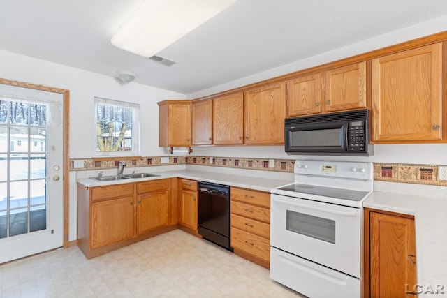 kitchen featuring a sink, black appliances, light floors, and light countertops