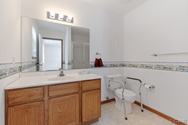 bathroom featuring a shower with shower door, toilet, vanity, baseboards, and tile patterned floors