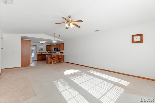 unfurnished living room featuring a ceiling fan, visible vents, vaulted ceiling, and light carpet