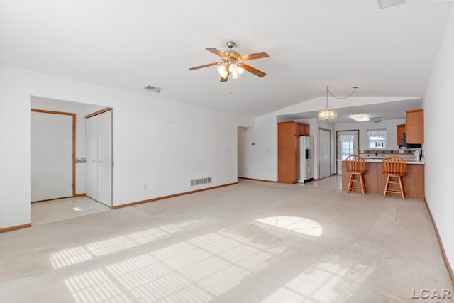 unfurnished living room featuring lofted ceiling, light carpet, visible vents, and ceiling fan with notable chandelier