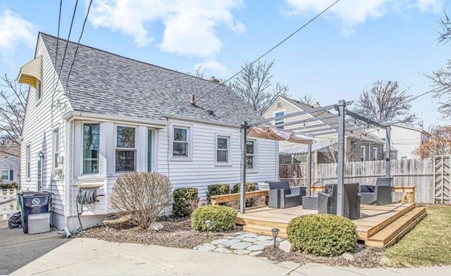 back of property with a deck, an outdoor hangout area, fence, roof with shingles, and a pergola