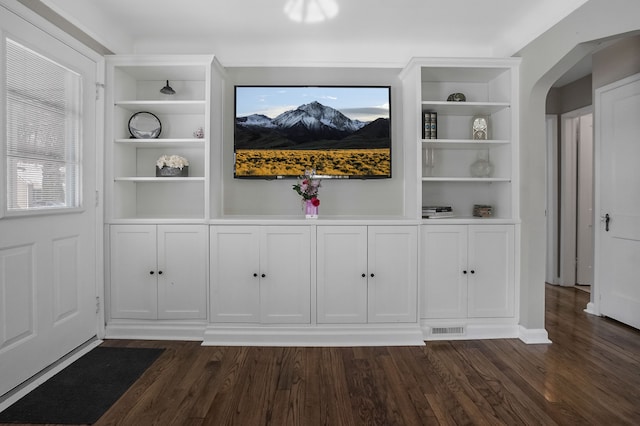 room details featuring visible vents, built in shelves, arched walkways, and wood finished floors