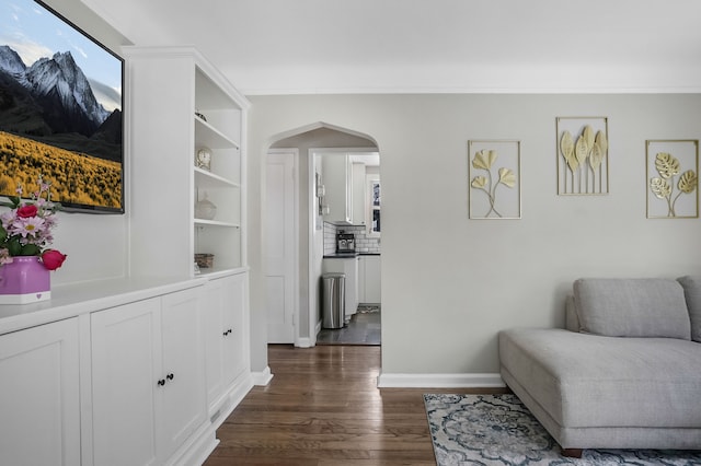 living area with arched walkways, dark wood finished floors, and baseboards